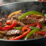 A close-up of beef stir-fry with colorful peppers in a wok.