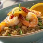 A close-up of a citrus shrimp rice bowl plated with vibrant natural lighting and soft shadows, highlighting its texture and delicate garnishes.